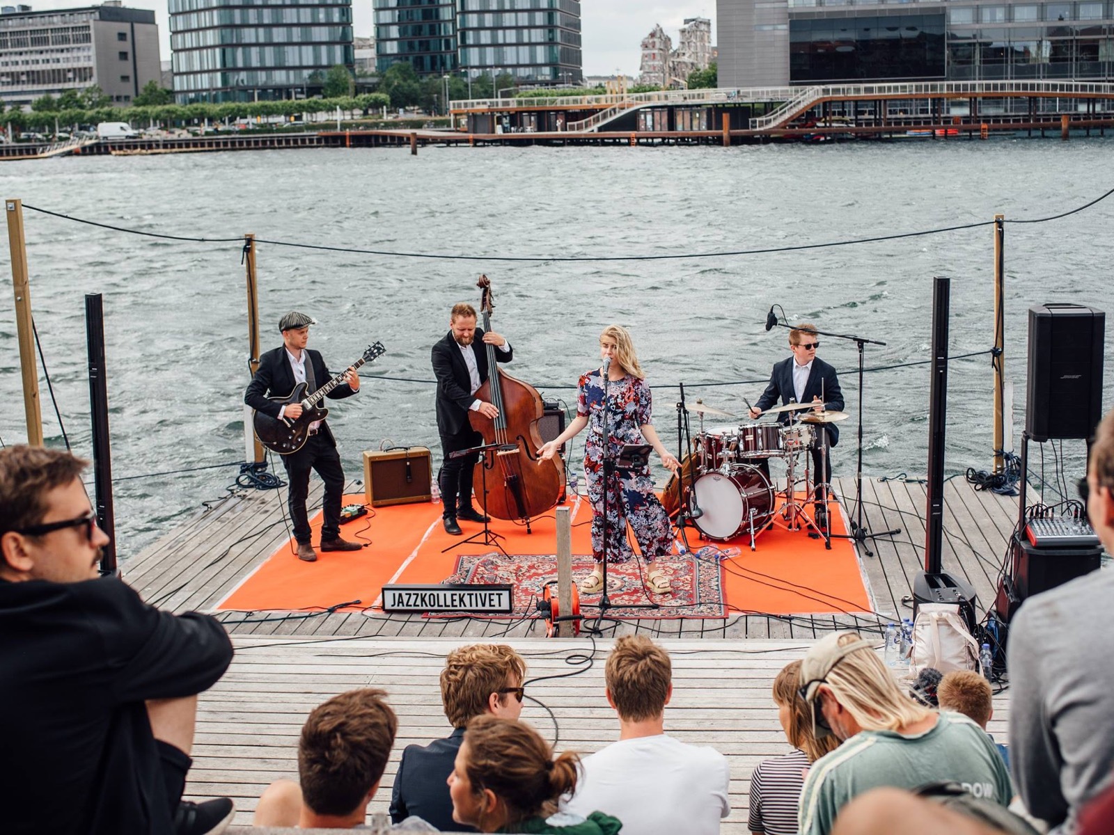 Et jazzband spiller på en tømmerflåde for publikum på kajen