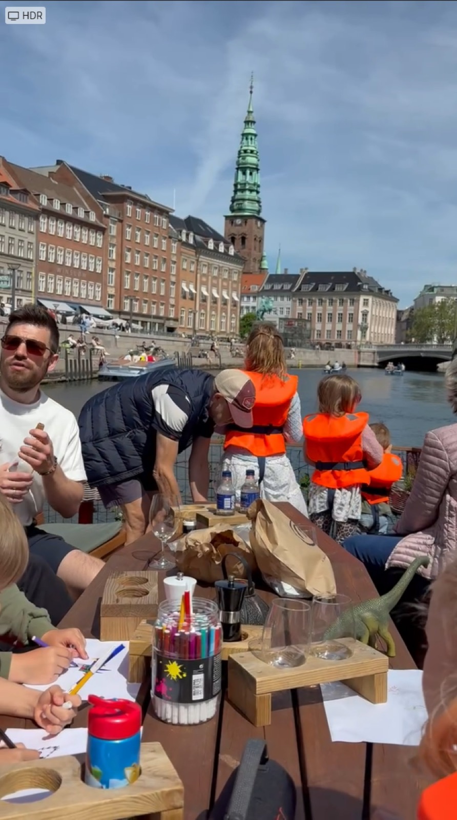 Familier om bord med tegnegrej på bordet og et kirketårn i baggrunden