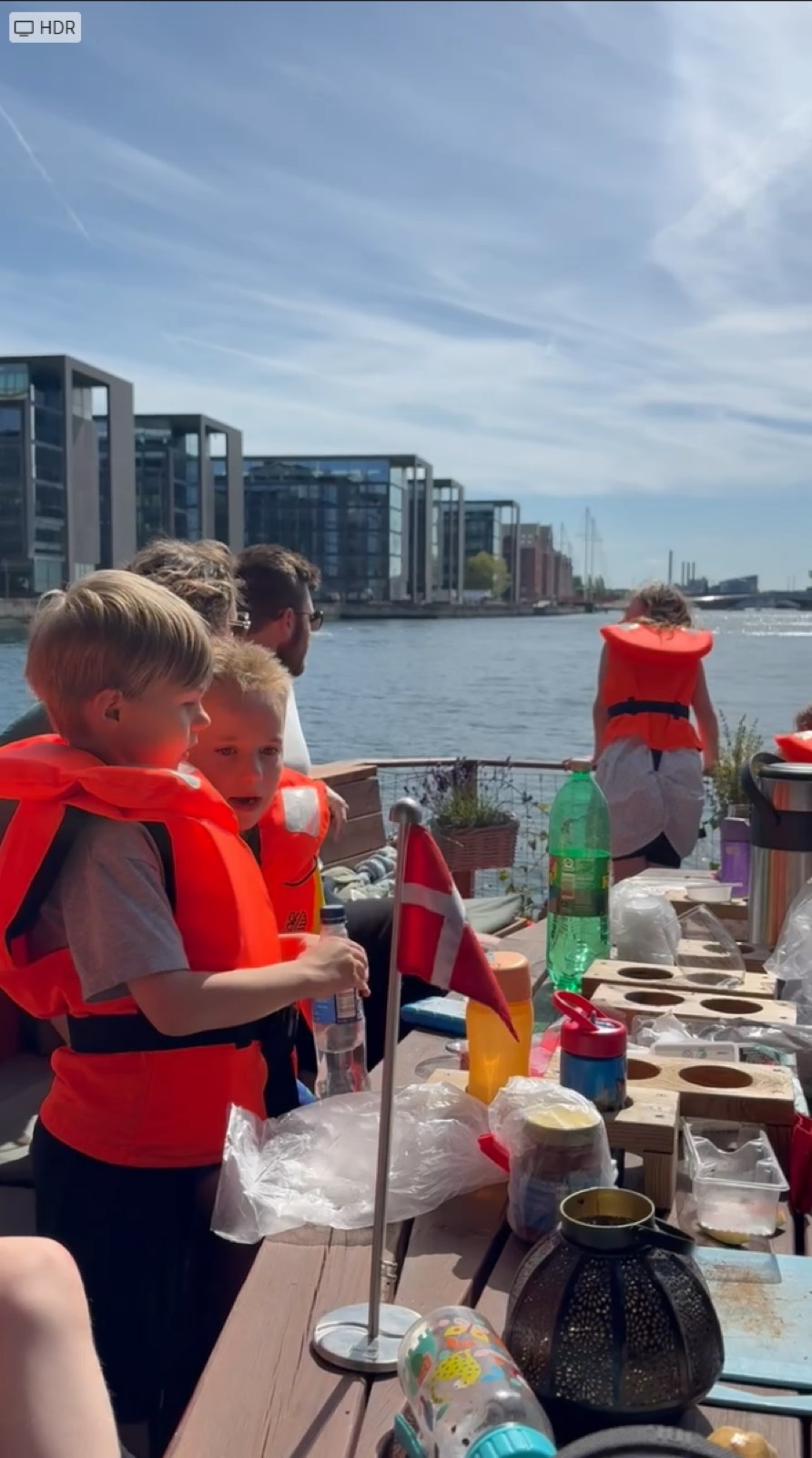 Børn i redningsveste ved bordet med tegnegrej om bord i havnen