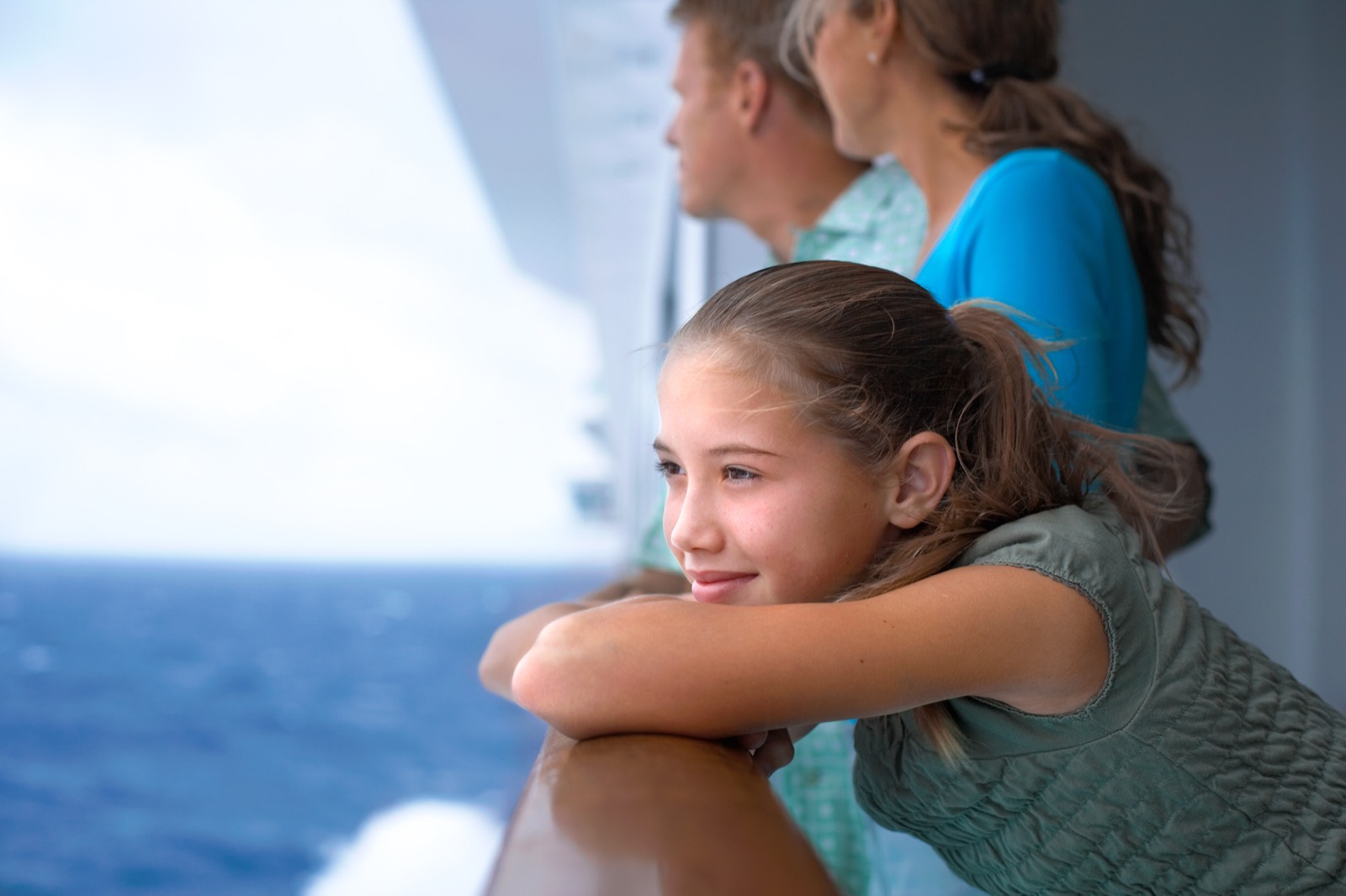 En pige og hendes familie læner sig mod rælingen og ser ud over havet